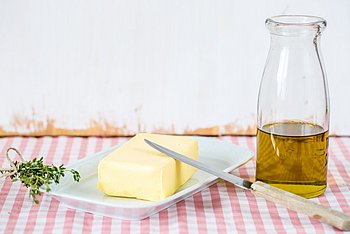 Hier sehen Sie Butter und eine Flasche mit Öl, die auf dem Tisch stehen.