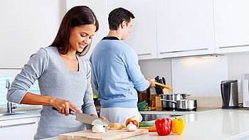 Mann und Frau stehen in der Küche und kochen Gerichte, die der Bauchspeicheldrüse gut tut