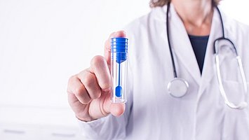 Eine Ärztin hält ein Röhrchen für die Stuhlprobe in der Hand