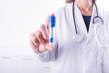 Eine Ärztin hält ein Röhrchen für die Stuhlprobe in der Hand