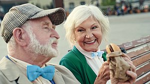 Ein älteres Ehepaar sitzt auf einer Parkbank und genießt das fettige Essen trotz einer Bauchspeicheldrüsenschwäche (exokrine Pankreasinsuffizienz).
