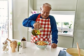 Ein älterer Herr gibt gutes Olivenöl zu seinen Spaghetti